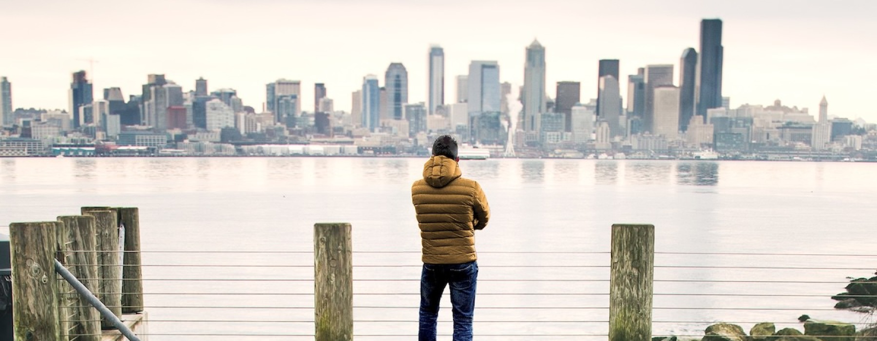 a man standing at a pier looking at a city